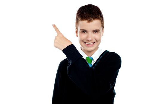 Happy young boy indicating upwards and smiling at camera