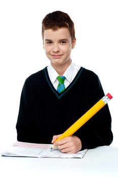 School boy writing on notebook with big yellow color pencil