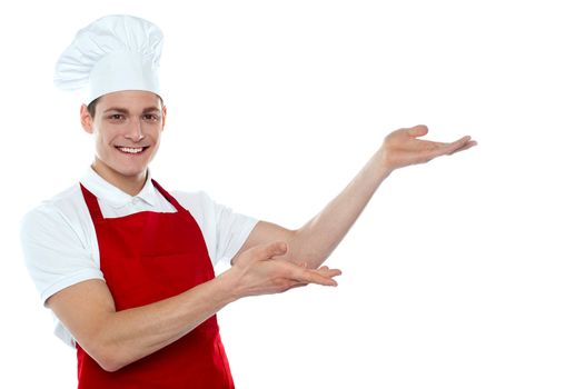 Male chef in red uniform presenting copy space isolated over white