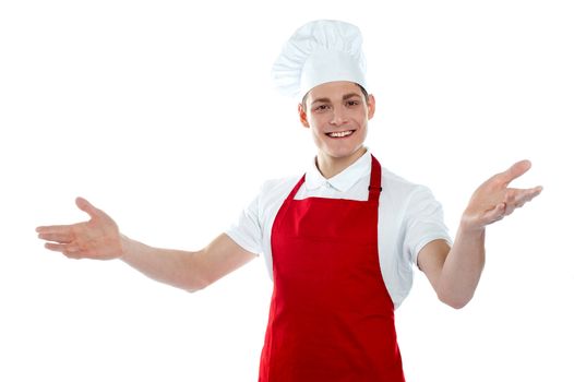 Handsome carefree male chef in a welcoming gesture isolated on white background