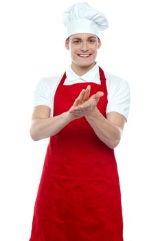 Isolated young handsome male chef clapping against white
