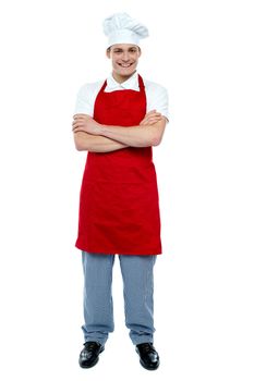 Handsome young cook posing in uniform with arms crossed, full length portrait