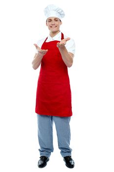 Full length portrait of handsome male cook welcoming you. At your service