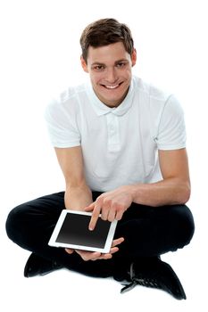 Seated guy with finger on touch pad device smiling at camera