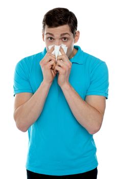 Young guy suffering from cold. Holding handkerchief and sneezing
