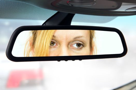 woman sits on driver's seat and Looks in the rear-view mirror