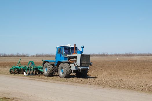 Blue tractor with a plow in a field