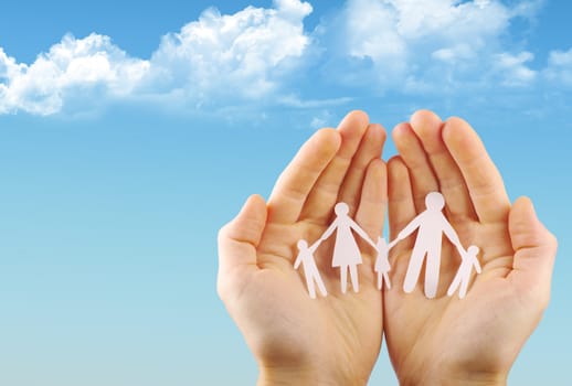 Paper family in hands isolated on blue sky
