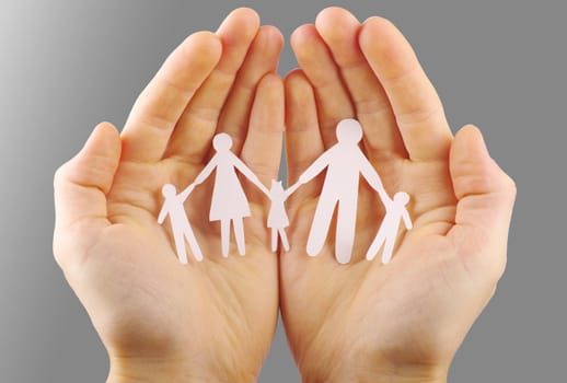 Paper family in hands isolated on grey background