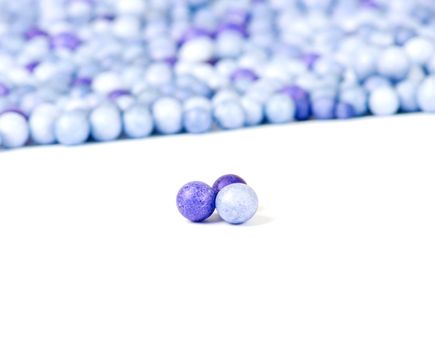 One blue and two violet little pearls isolated on background of other pearls.