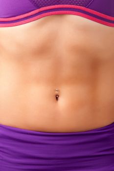 Closeup of a fit woman's abs with a pierced belly button