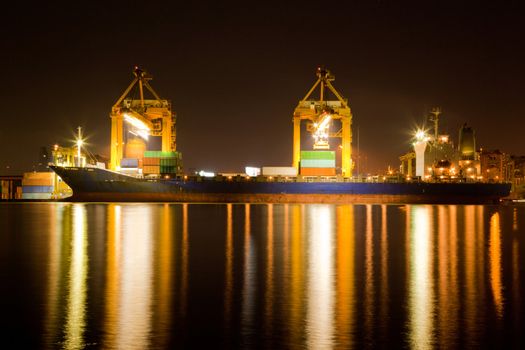 Container Cargo freight Industrial ship with working crane bridge unloading and loading goods in Bangkok shipyard Terminal at night for Logistic Import Export background