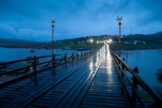 Wood bridge at night with river and mountain in Kanchanaburi Thailand