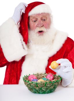Santa Claus in authentic look confused about easter eggs. All on white background.