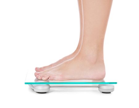 Female person standing on weight scale. All on white background.