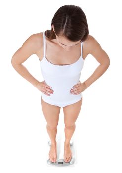 Attractive young woman in white underwear standing on weight scale. All on white background.