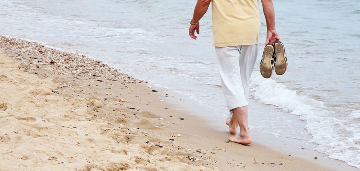 Retired person doing a beach stroll.