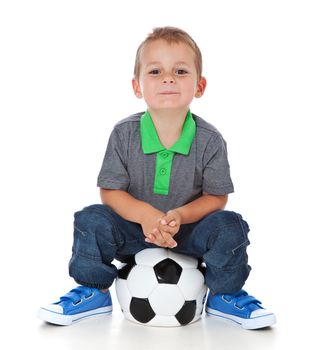 Full length shot of a cute little boy sitting at a soccer ball. All isolated on white background.