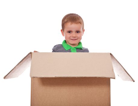 Cute litte boy sitting in a box. All isolated on white background.
