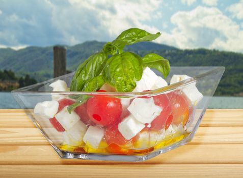 Glass cup of salad with cheese, tomatoes and basil
