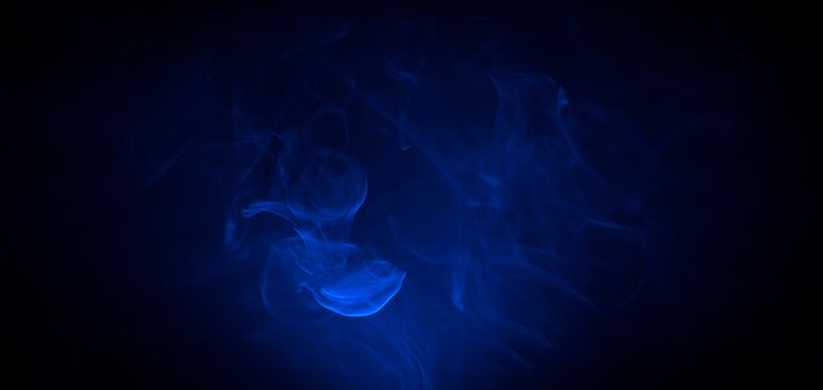 Blue smoke in the dark on black background