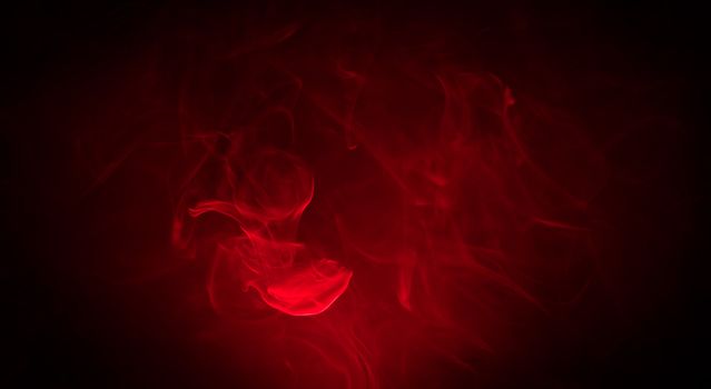 Red smoke in the dark on black background