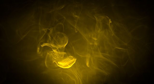 Yellow smoke in the dark on black background