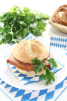 Roll with beef and pork loaf, mustard, parsley on a light background
