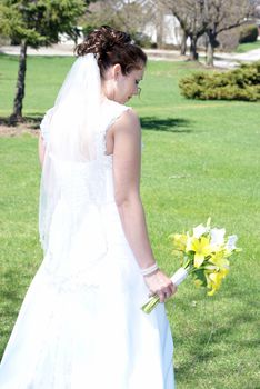 A bride looks at her flower bouquet in her hands.