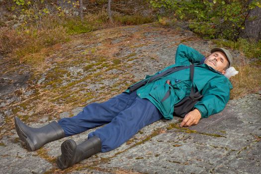 An elderly tourist resting lying on the rock