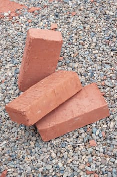 Three red clay bricks lying on the gravel