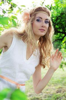 Romantic woman in white dress walking among trees