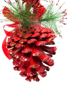 Red christmas pine cone and ribbons on white.