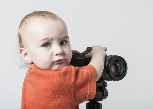 young child with digital SLR camera on grey background