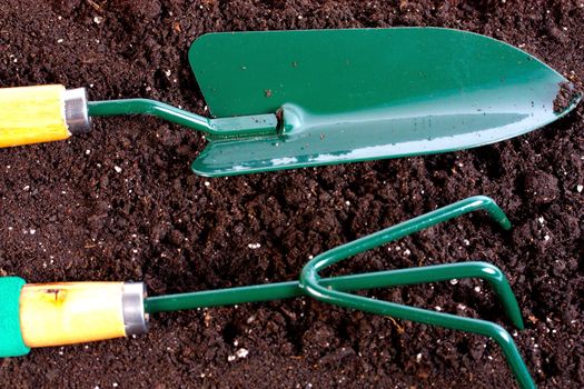 Garden tool with heap of organic compost background