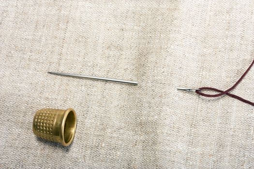 needle , thimble and thread on background fabrics concept