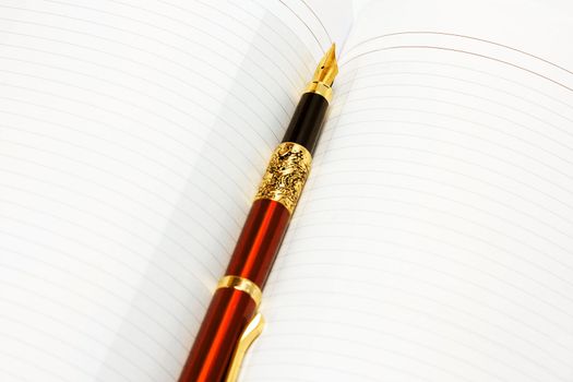 golden pen on diary book with blank page