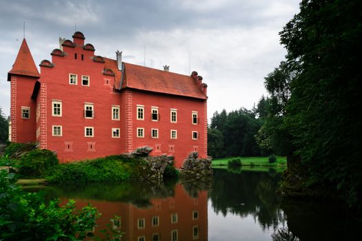 Large red house on lake with forest on background