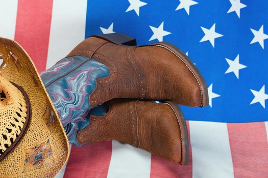 cowboy boots and straw hat on American flag background