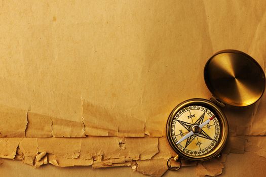 Antique brass compass over old paper background