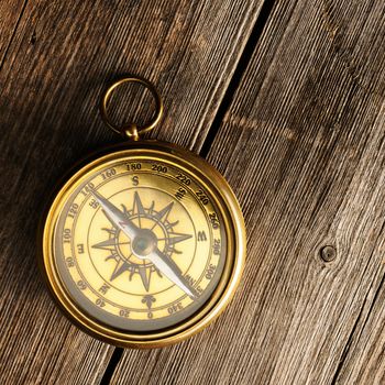 Antique brass compass over wooden background