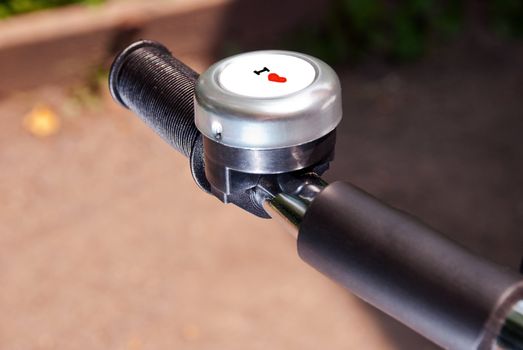 Bicycle handle with signal bell with symbol "I love" closeup.