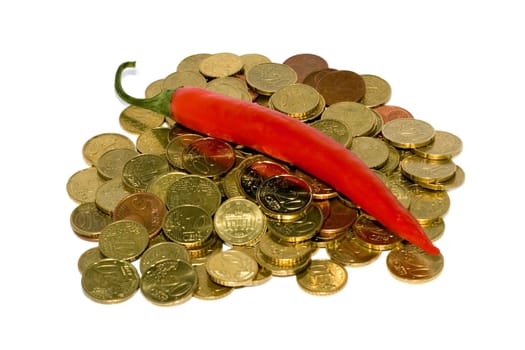 Heap of coins and red hot chili peppers isolated on white background