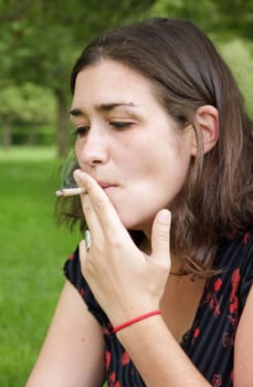 woman smoking outdoors, a rolled cigarette