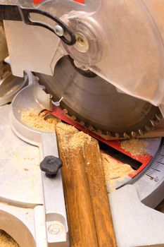 electric saw cuts plank a plinth under corner 45 degrees.