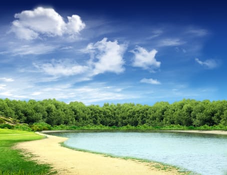 Landscape: country road along the lake with woods and blue sky in the background