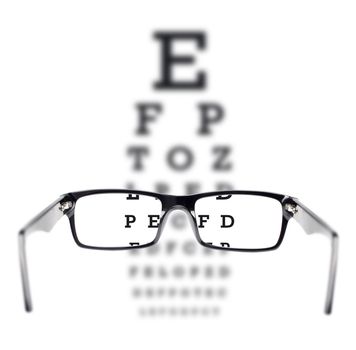 Sight test seen through eye glasses, white background isolated