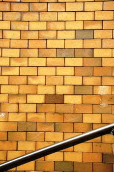 Background of yellow brick wall and steel stair railing.