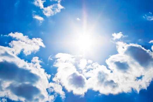 Bright sunrays in a blue cloudy sky