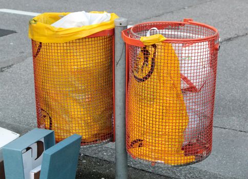 Two orange garbage bins with the streetl on the background